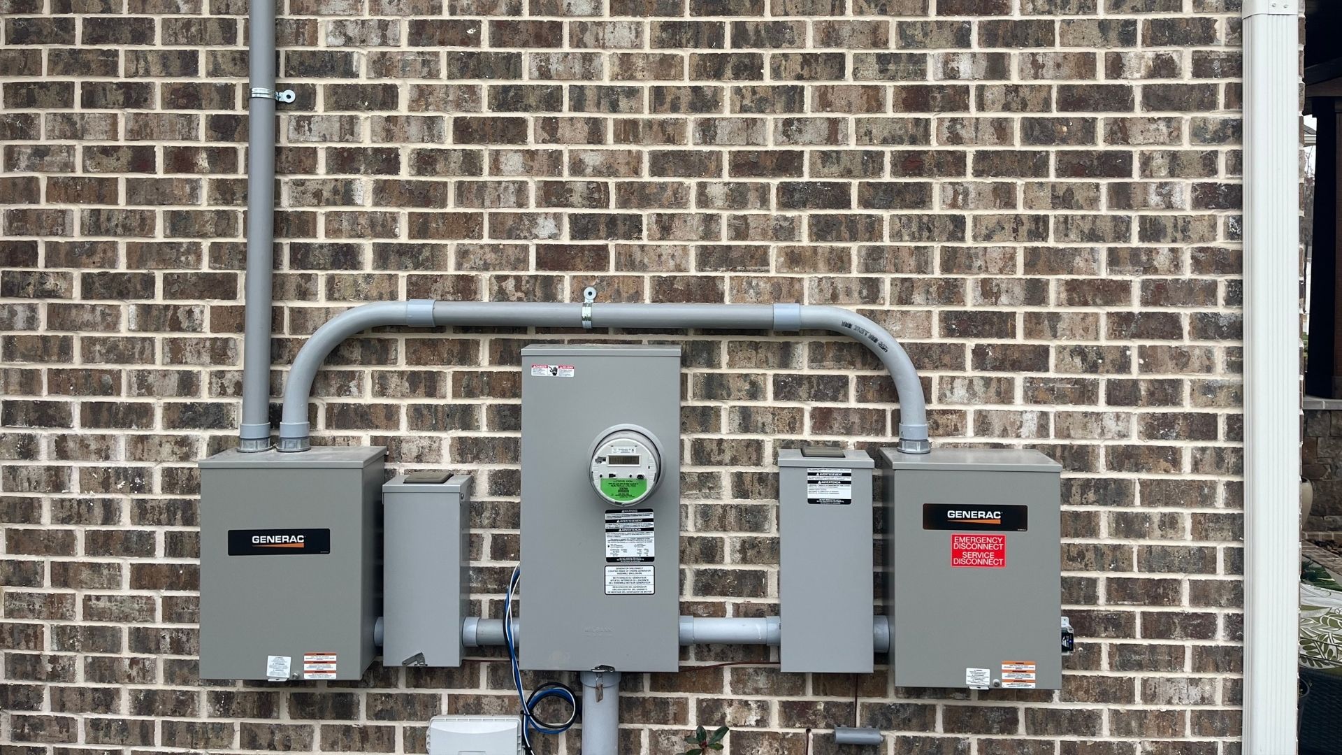 Generac electrical equipment mounted on brick wall with utility meter